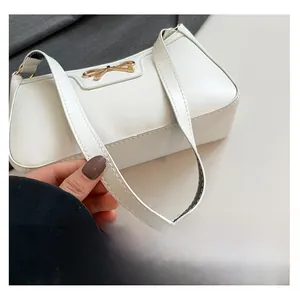Close-up of a white crescent shoulder bag featuring a golden bow metal buckle detail
