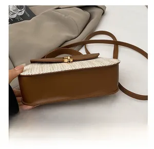 Detail showing the wear-resistant bottom of a woven straw crossbody bag with leather trim