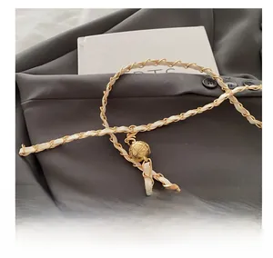 Detail of golden ball clasp and woven cream leather chain on a bucket bag strap