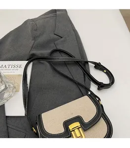 Close-up of saddle bag with beige canvas, black leather trim and gold metal buckle lock