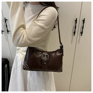 Detail of dark brown leather bag with silver rivets and decorative buckle on a model