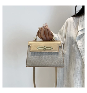 Detail of glitter champagne handbag with gold metal twist lock and leather stitching