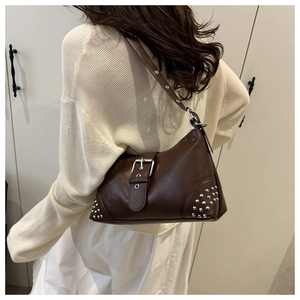 Detail of dark brown baguette bag with silver rivets and adjustable metal eyelet strap