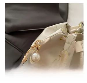 Macro view of golden clasp and decorative pearl chain on the floral bucket bag