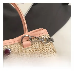 Detail of silver metal hook and pink leather trim on the woven straw shoulder bag