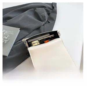 Detail showing the spacious interior of this contrast color square bag with makeup items