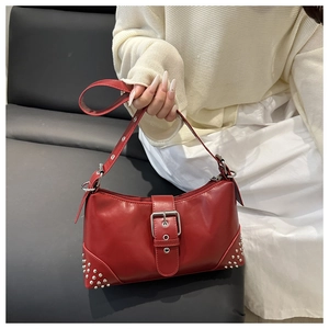 Close-up of a vintage red crescent underarm bag with silver rivets and buckle detail