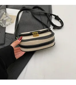 Detail of canvas and black PU leather saddle bag with gold buckle on grey blazer