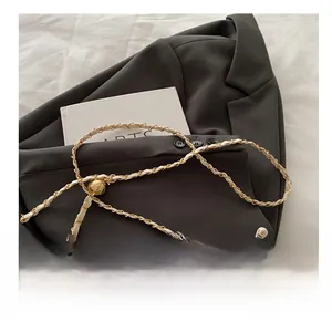 Detail of elegant pearl handle and gold chain strap on embroidered bucket bag