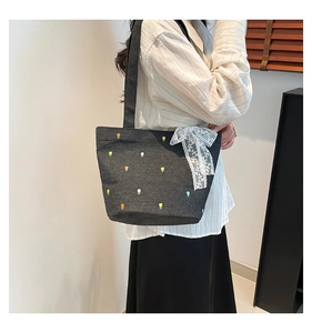 Detail of dark gray denim tote bag with colorful tulip embroidery and lace bow