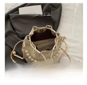 Interior capacity of embroidered bucket bag showing phone and wallet with pearl chain