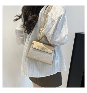 Detail of gold sequin patchwork crossbody bag worn by a model against a white wall