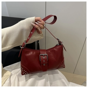 Detail of burgundy leather shoulder bag with silver buckle and punk style metal rivets