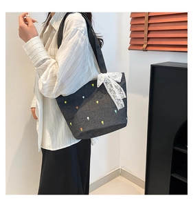 Detailed shot of denim tote bag featuring floral embroidery and large lace bow detail
