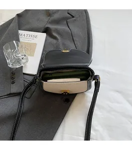 Detail view of contrast color saddle bag interior with phone and wallet inside