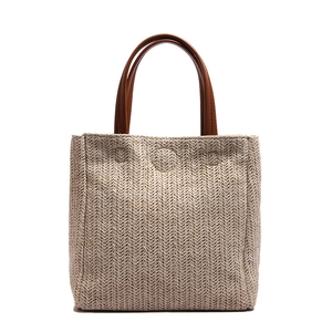 Handwoven straw tote bag with contrast brown leather handles and herringbone weave pattern