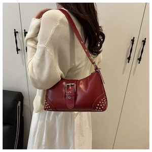 Detail of red leather tote bag showing silver rivets and side belt buckle design