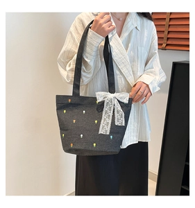 Detail of tulip flower embroidery and white lace bow on grey denim tote bag