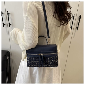 Blue tweed box bag shown as a crossbody on a model in a cozy indoor home setting