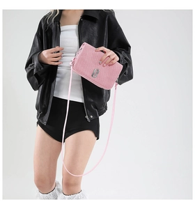 Detailed view of the sparkling pink fabric texture and silver metal logo on small square bag
