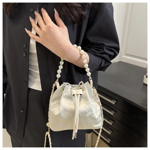 Detail of champagne satin bucket bag with pearl handle and jacquard floral embroidery