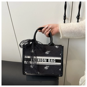 Detail of black tote with white rose jacquard patterns and a lace bow decoration