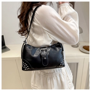 Detail of black leather shoulder bag with silver buckles and punk style rivets