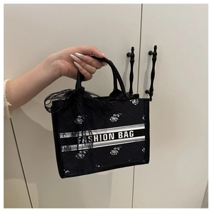 Detail of black tote bag featuring white rose pattern and black lace bow on handle
