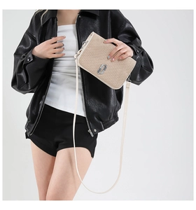 Model wearing a cream textured crossbody bag with metal double-J logo on black leather jacket