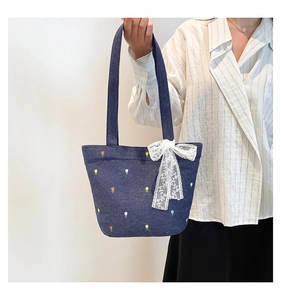 Detail of denim tote bag featuring embroidered tulips and a white lace bow accent