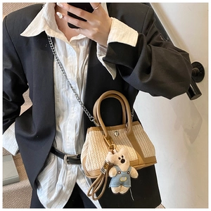 Detailed shot of straw woven crossbody bag featuring leather trim and cute plush bear charm