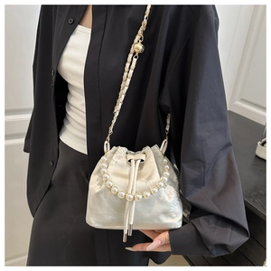 Detail of embroidered satin bucket bag with pearl handle and golden chain strap