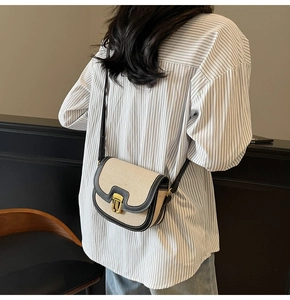 Detail view of contrast stitch saddle bag with gold metal buckle and woven texture