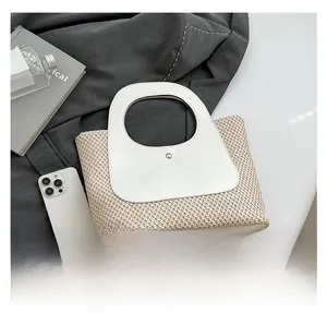Detail of retro straw tote bag with faux leather handle and metal button closure detail