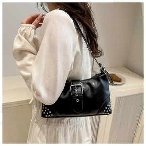 Detail of black leather tote bag featuring silver studs and adjustable metal buckle strap