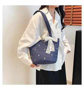 Detail of denim tote bag featuring tulip embroidery and white lace bow decoration