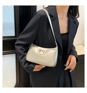 Detailed close-up of a silver leather shoulder bag featuring a gold bow metal buckle