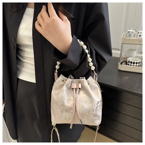 Detail of jacquard bucket bag featuring mountain patterns and a large pearl handle