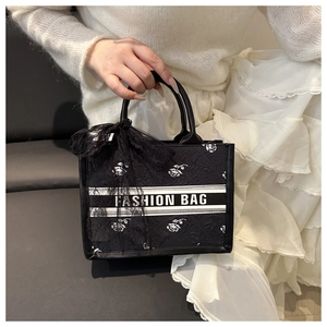 Detail of black lace tote with white rose embroidery and elegant bow accessory
