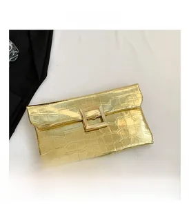 Detail of gold crocodile-embossed envelope clutch with a square metallic buckle