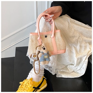 Detail of woven straw handbag with pink leather trim and a cute plush bear charm