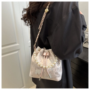 Detail of pink embroidered bucket bag with pearl handle and golden ball chain strap