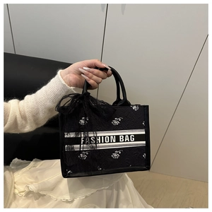 Detail of black tote with rose embossing, lace bow, and Fashion Bag logo strap