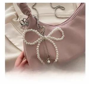 Detail of pink hobo bag with pearl bow charm and silver heart pendant detail