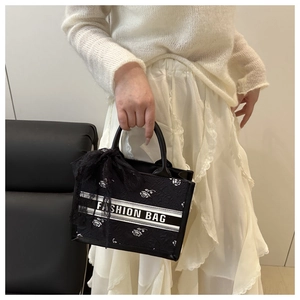 Detail of black lace tote with white rose pattern and a stylish black lace bow handle