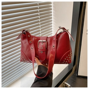 Close-up of red leather tote bag with silver buckle strap and rivet stud details