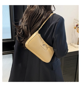 Sac sous le bras croissant beige chic avec nœud en métal porté par un mannequin
