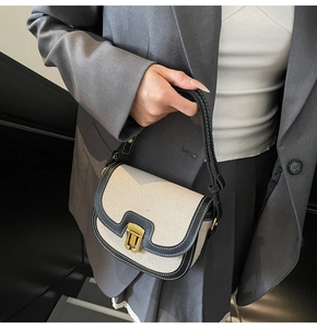 Detail of retro canvas saddle bag with black leather trim and golden metal lock