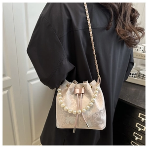 Detailed embroidery on a pearl chain bucket bag shown in a real-life modeling scene