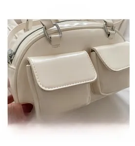 Detail of cream glossy leather baguette bag featuring two front flap pockets and silver hardware
